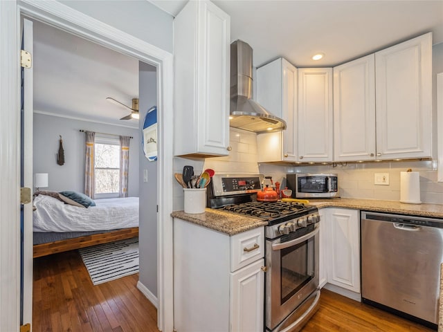 kitchen with white cabinetry, wall chimney range hood, and appliances with stainless steel finishes