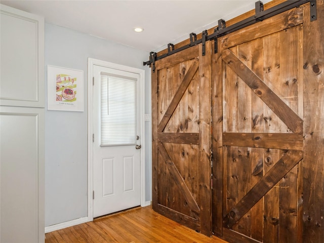 entryway with a barn door, baseboards, and wood finished floors