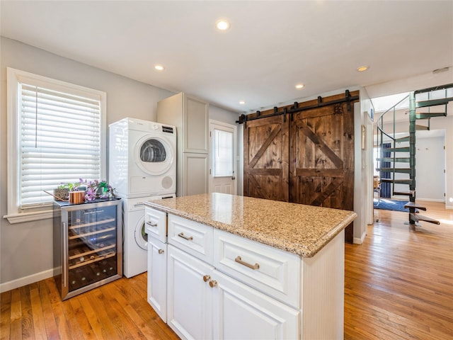 kitchen featuring wine cooler, plenty of natural light, light wood-style floors, and stacked washing maching and dryer