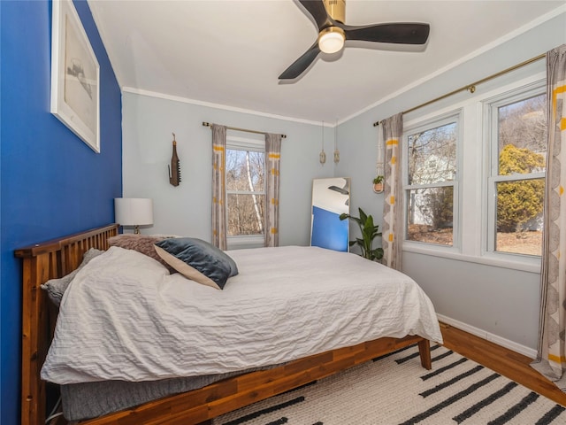 bedroom featuring a ceiling fan, wood finished floors, baseboards, and ornamental molding