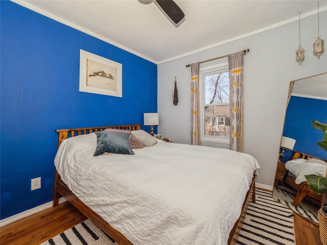 bedroom featuring a ceiling fan, crown molding, baseboards, and wood finished floors