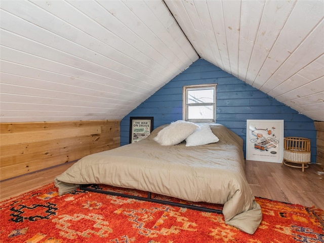 bedroom featuring lofted ceiling, wood finished floors, wood walls, and wooden ceiling