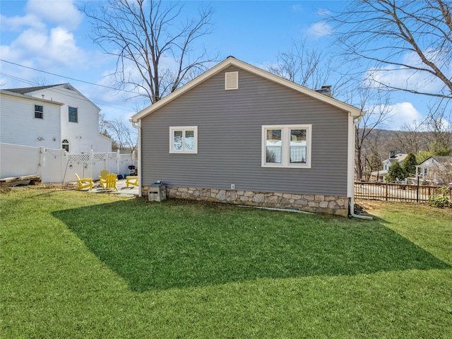 rear view of house featuring a lawn, a chimney, and fence