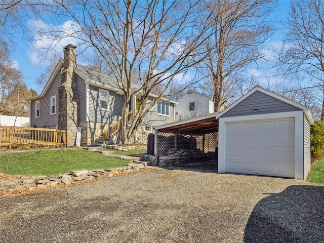 exterior space with a front lawn, a chimney, an outdoor structure, a carport, and driveway