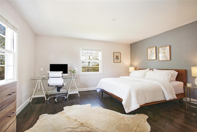 bedroom with wood finished floors, visible vents, baseboards, and multiple windows