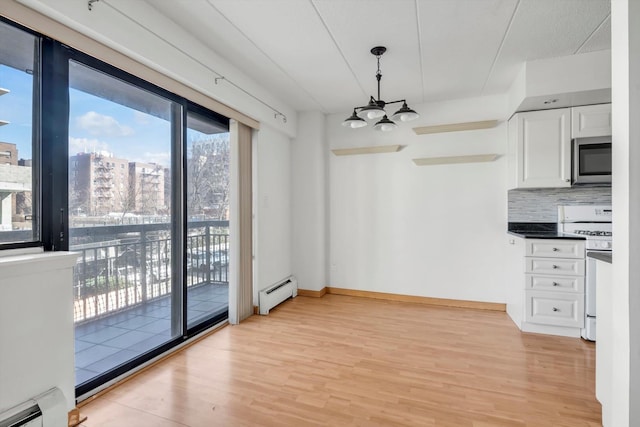 unfurnished dining area featuring a baseboard heating unit, a notable chandelier, and light wood-style floors