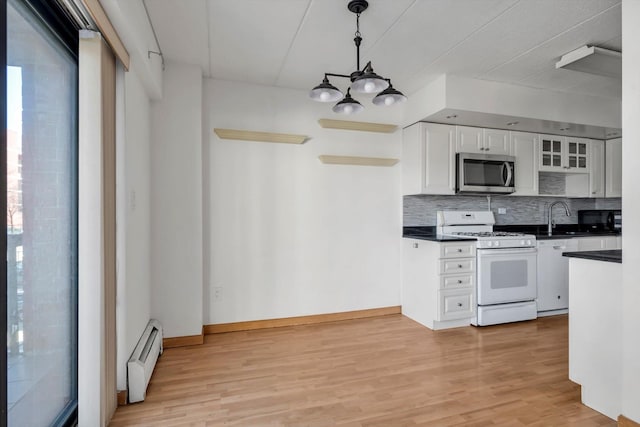 kitchen featuring dark countertops, a baseboard radiator, decorative backsplash, stainless steel microwave, and white gas range