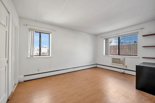 empty room with a wall mounted air conditioner, a textured ceiling, baseboard heating, and wood finished floors