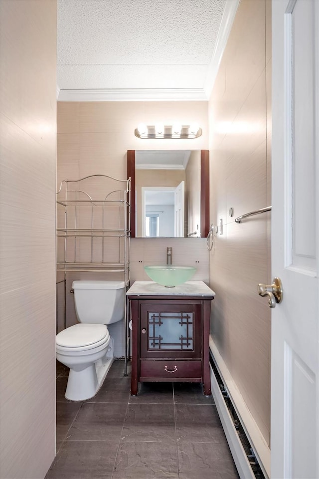 bathroom featuring a baseboard heating unit, crown molding, toilet, vanity, and a textured ceiling