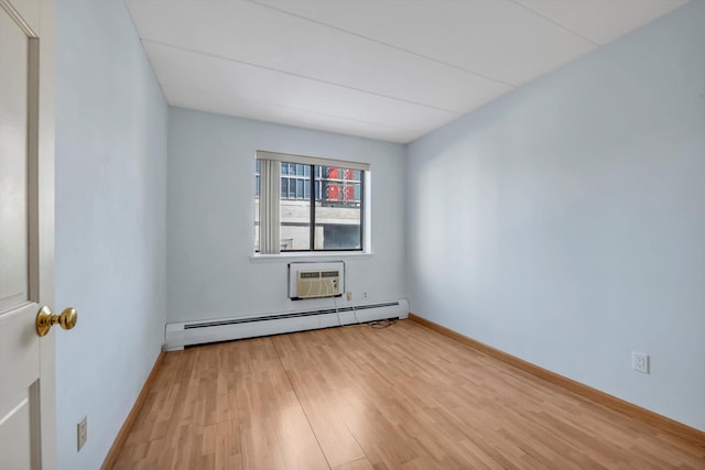 spare room featuring a wall mounted air conditioner, a baseboard radiator, baseboards, and light wood finished floors