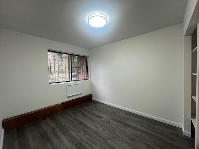 unfurnished room with dark wood-type flooring and baseboards