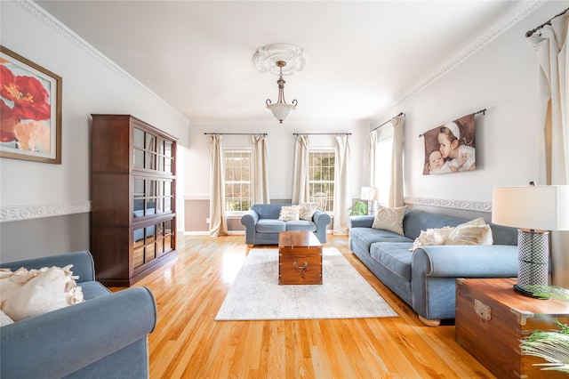 living area with baseboards, light wood-style floors, and ornamental molding