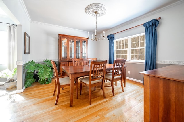 dining room featuring a chandelier, crown molding, light wood-type flooring, and baseboards