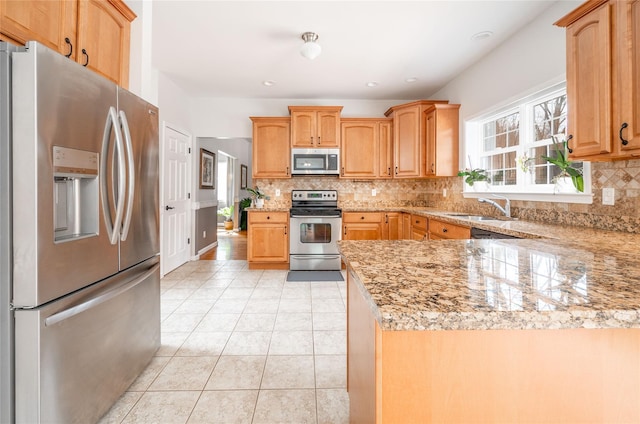 kitchen featuring light stone counters, light tile patterned floors, a sink, appliances with stainless steel finishes, and tasteful backsplash