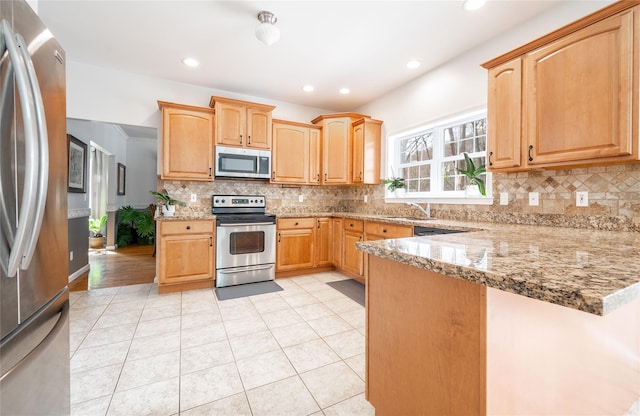 kitchen with tasteful backsplash, light tile patterned floors, a peninsula, and stainless steel appliances