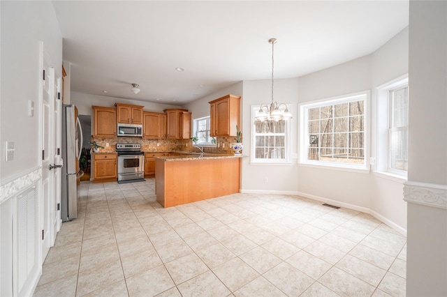 kitchen with tasteful backsplash, visible vents, appliances with stainless steel finishes, a peninsula, and an inviting chandelier