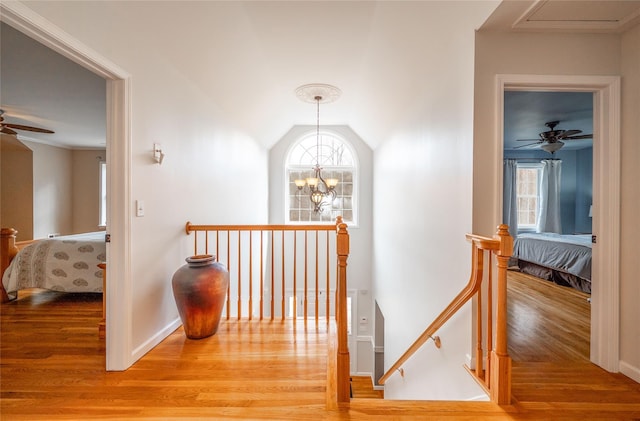 hallway featuring an upstairs landing, a notable chandelier, a wealth of natural light, and wood finished floors