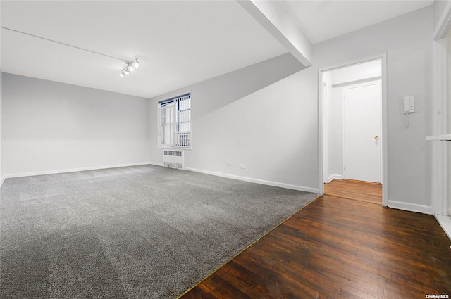 empty room with radiator heating unit, wood finished floors, baseboards, and carpet floors