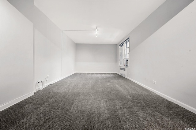 unfurnished room featuring dark carpet, radiator, and baseboards