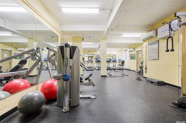 workout area featuring a wall mounted air conditioner and concrete block wall