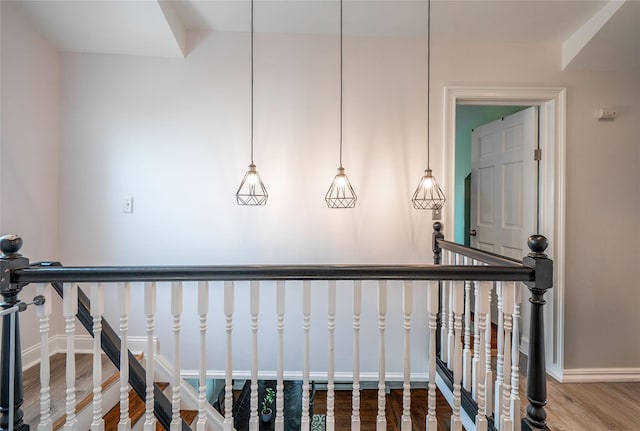 hall with an upstairs landing, baseboards, and wood finished floors