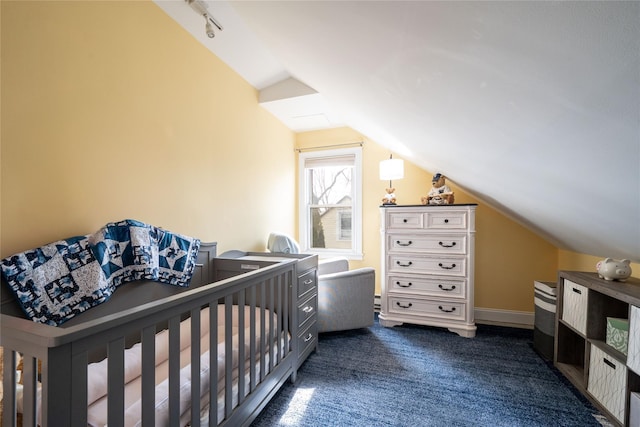 bedroom with dark colored carpet, baseboards, track lighting, and vaulted ceiling