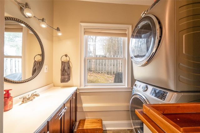 laundry room with cabinet space, stacked washer and clothes dryer, and a sink