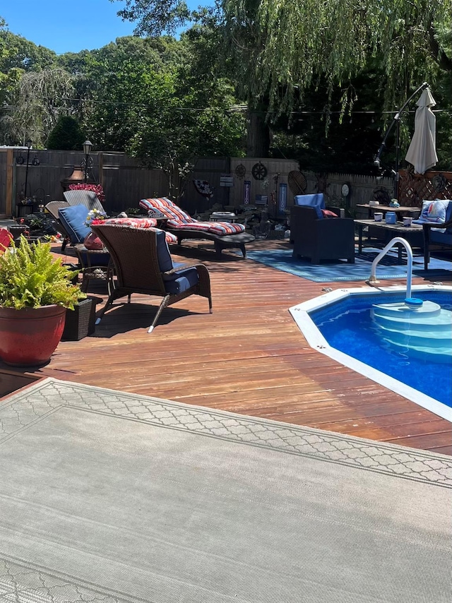 view of pool with an outdoor living space, a deck, and fence