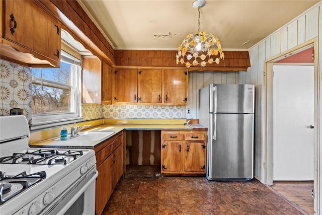 kitchen featuring brown cabinets, white gas range, light countertops, and freestanding refrigerator