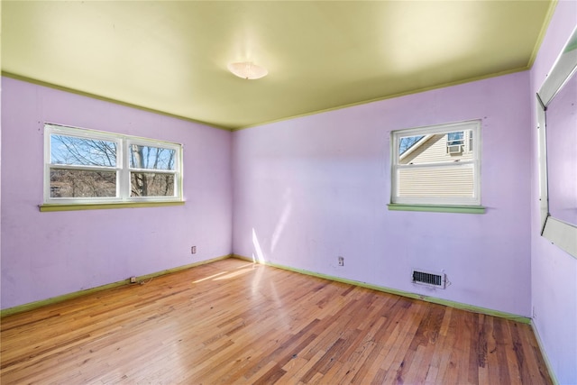 spare room featuring visible vents, baseboards, and wood-type flooring