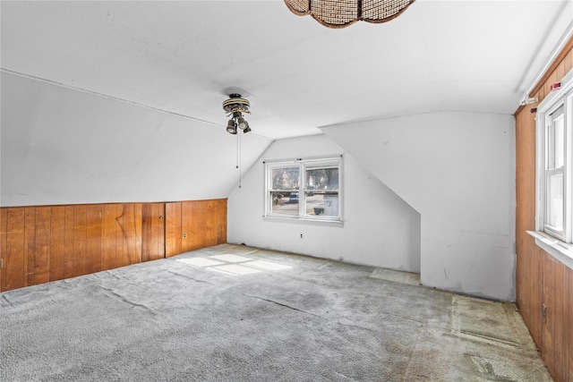 additional living space with wood walls, carpet flooring, and vaulted ceiling