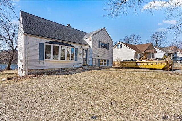 split level home featuring a chimney, roof with shingles, and a front yard