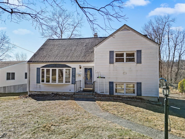 split level home featuring a front yard, a chimney, and a shingled roof