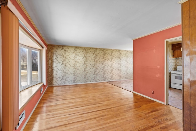 empty room with baseboards, wallpapered walls, light wood-style floors, a baseboard heating unit, and crown molding