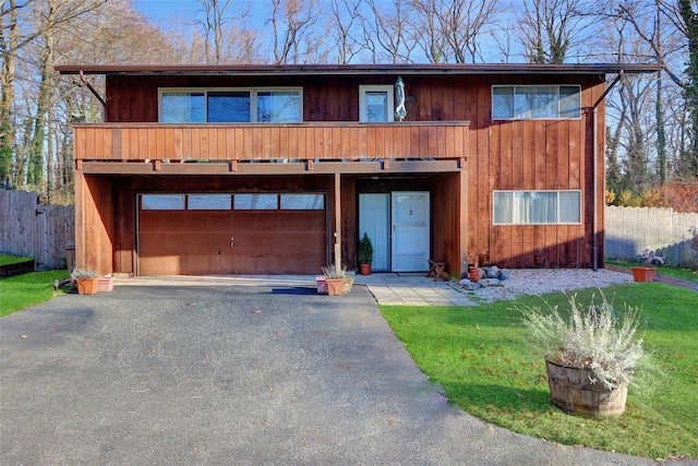 chalet / cabin featuring aphalt driveway, a garage, and fence