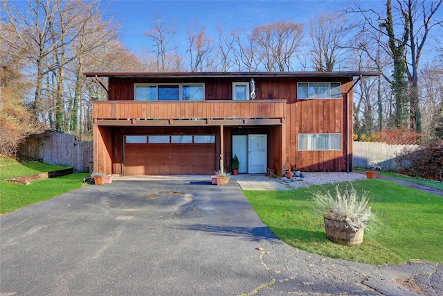 view of front facade featuring aphalt driveway, a garage, a front yard, and fence