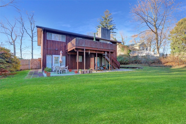 rear view of house with a lawn, a patio, fence, stairway, and a chimney