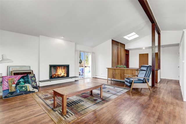 living area with lofted ceiling with skylight, hardwood / wood-style flooring, and a warm lit fireplace