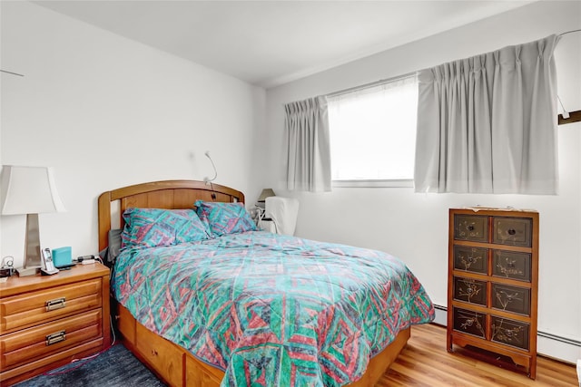 bedroom featuring baseboard heating and wood finished floors