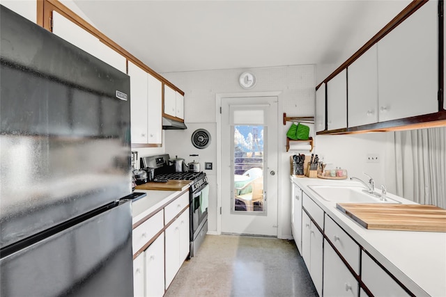 kitchen with white cabinetry, light countertops, freestanding refrigerator, and stainless steel gas range oven