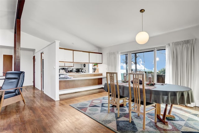 dining room featuring a baseboard heating unit, vaulted ceiling with beams, and hardwood / wood-style floors