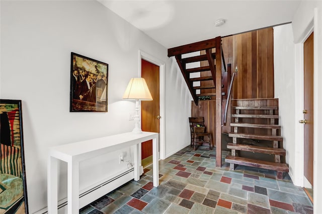 stairway featuring a baseboard radiator and stone finish floor