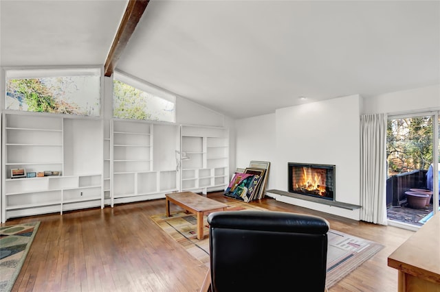 living room with baseboard heating, a warm lit fireplace, wood finished floors, and vaulted ceiling with beams