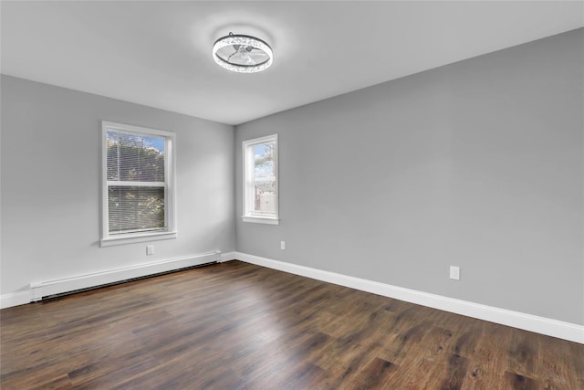 spare room with baseboard heating, baseboards, and dark wood-style flooring