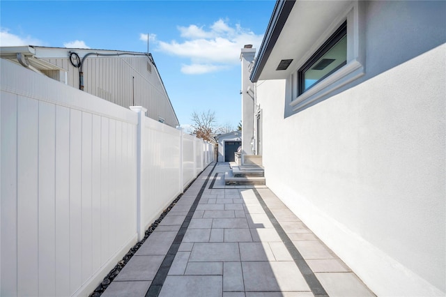 view of side of property featuring an outdoor structure, fence, and stucco siding