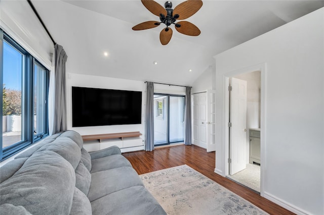 living area with lofted ceiling, wood finished floors, baseboards, and a healthy amount of sunlight