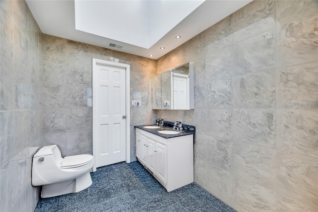 bathroom with visible vents, toilet, vanity, recessed lighting, and tile walls