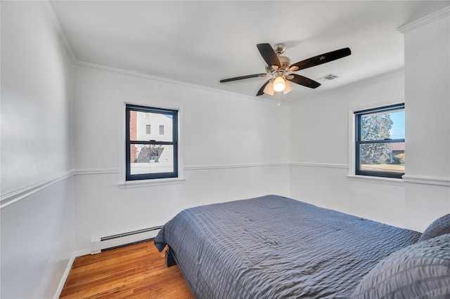 bedroom featuring wood finished floors, visible vents, a ceiling fan, a baseboard heating unit, and crown molding