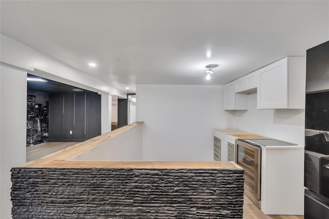 kitchen with light wood-type flooring, beverage cooler, white cabinetry, recessed lighting, and light countertops