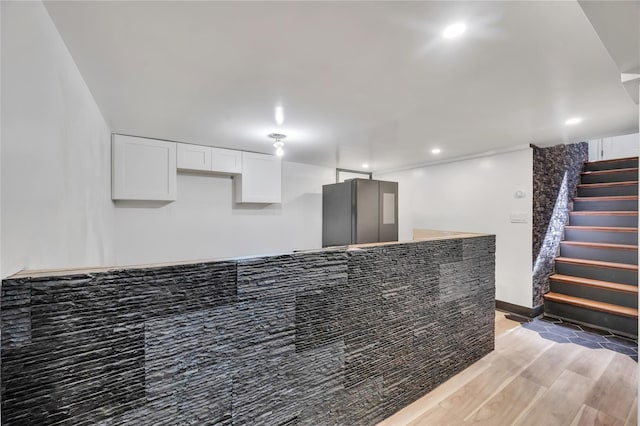 kitchen featuring baseboards, light wood-style flooring, recessed lighting, freestanding refrigerator, and white cabinets